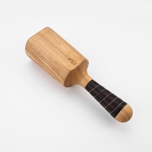 May include: A wooden mallet with a black leather handle. The mallet has a square head and is marked with the letters "XO".