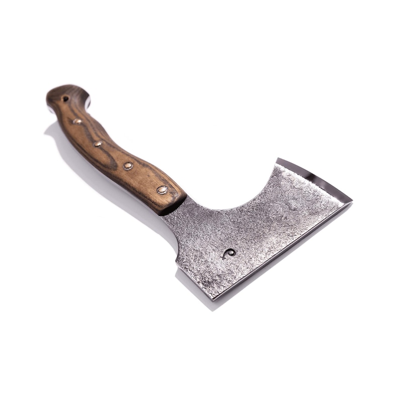 May include: A small, hand-forged axe with a wooden handle. The axe head is made of dark metal and has a curved blade. The handle is a light brown color and is secured with small metal rivets. The axe is designed for chopping and cutting.