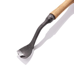 May include: A curved wood carving tool with a wooden handle and a metal blade. The blade is curved and has a sharp edge. The tool is used for carving wood.