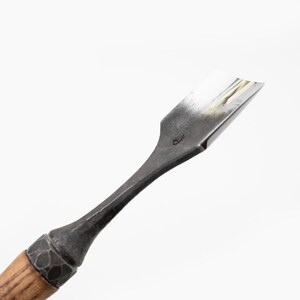 May include: A close-up of a wood-handled carving tool with a curved metal blade. The blade is marked with the number "6".