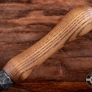 May include: Close-up of a wooden handle with a dark brown stain. The handle is smooth and has a slight curve. The handle is attached to a metal tool.