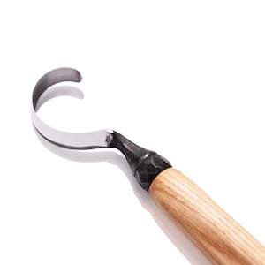 Peut inclure: Un outil de sculpture sur bois avec une lame incurvée et un manche en bois. La lame est en métal et a une pointe acérée. Le manche est en bois et a une surface texturée.
