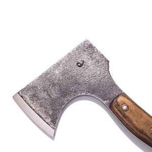 May include: A small, rustic axe with a textured, gray metal head and a polished, silver blade. The wooden handle is a warm brown, secured with metal rivets. The head features a small, etched design.
