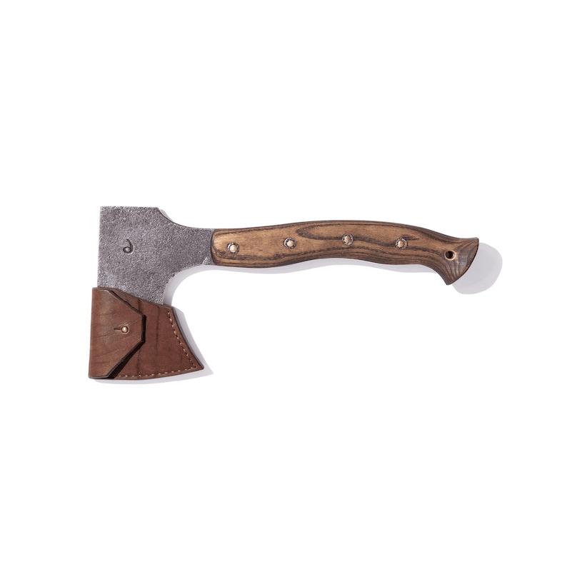 May include: A small hatchet with a wooden handle and a metal head. The handle is a light brown color with dark brown accents. A brown leather sheath protects the blade. The hatchet is designed for outdoor use.