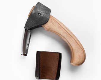 Può includere: Un'ascia da mano nera e argentata con manico in legno e fodero in pelle marrone. L'ascia ha un piccolo anello di metallo sul manico.