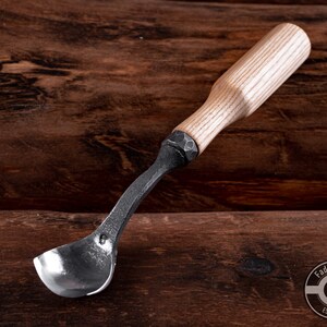 May include: A wooden handled spoon carving tool with a metal scoop. The tool is made by Fadir Tools, Est. 2016.