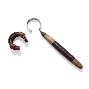Peut inclure: Une sangle en cuir marron avec un crochet en métal et un outil à manche en bois avec un crochet en métal.