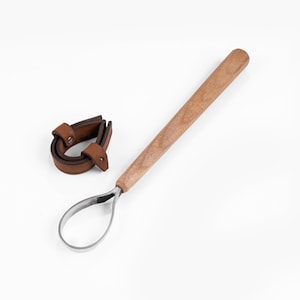 Peut inclure: Un outil en cuir brun avec une poignée en bois et une boucle en métal. L'outil est utilisé pour la fabrication d'artisanat en cuir.