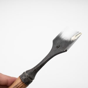 May include: A close-up of a wood-handled chisel with a black metal blade. The blade is marked with the number "6".