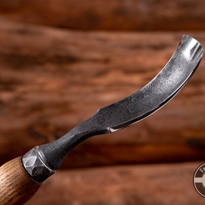 May include: A curved wood carving tool with a wooden handle and a metal blade. The blade is curved and has a sharp edge. The handle is made of wood and has a textured surface. The tool is made by Fadir Tools, Est. 2016.