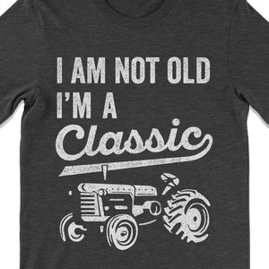 May include: Dark gray t-shirt with white text that reads "I am not old I'm a Classic" and a vintage tractor graphic.