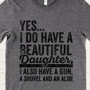 May include: Gray t-shirt with a humorous saying: "YES... I DO HAVE A BEAUTIFUL Daughter, I ALSO HAVE A GUN, A SHOVEL AND AN ALIBI"