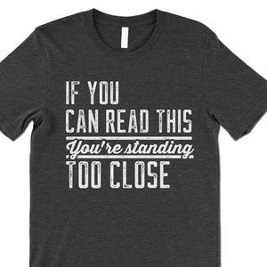 May include: Dark gray t-shirt with white text that reads "If you can read this you're standing too close".