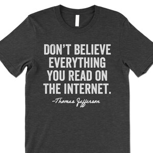 May include: Dark grey t-shirt with a white print that reads "Don't believe everything you read on the internet. -Thomas Jefferson"