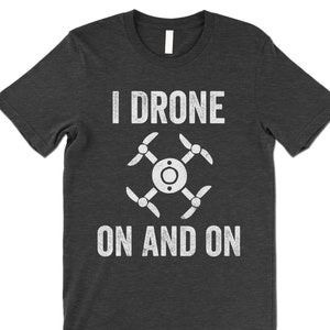 Op de afbeelding: Een donker grijs gem&ecirc;leerd t-shirt met een witte afbeelding van een drone en de tekst "I drone on and on".