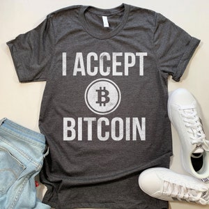 May include: A dark gray t-shirt with white text that reads "I ACCEPT BITCOIN" with a Bitcoin symbol in between the words.