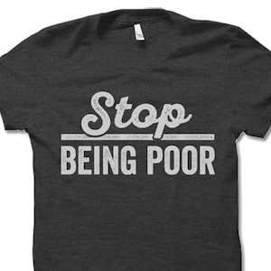 May include: A dark gray t-shirt with a white graphic that says "Stop Being Poor" in a vintage style font.