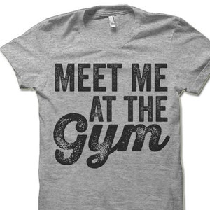 May include: Gray t-shirt with the text "Meet Me At The Gym" in black, distressed lettering.