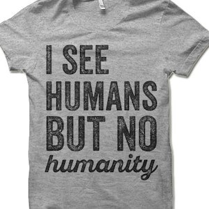May include: A heather grey t-shirt with a distressed black graphic that reads "I see humans but no humanity".