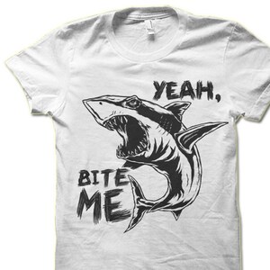 May include: White t-shirt with a black and white graphic of a shark with its mouth open and the text "Yeah, Bite Me".