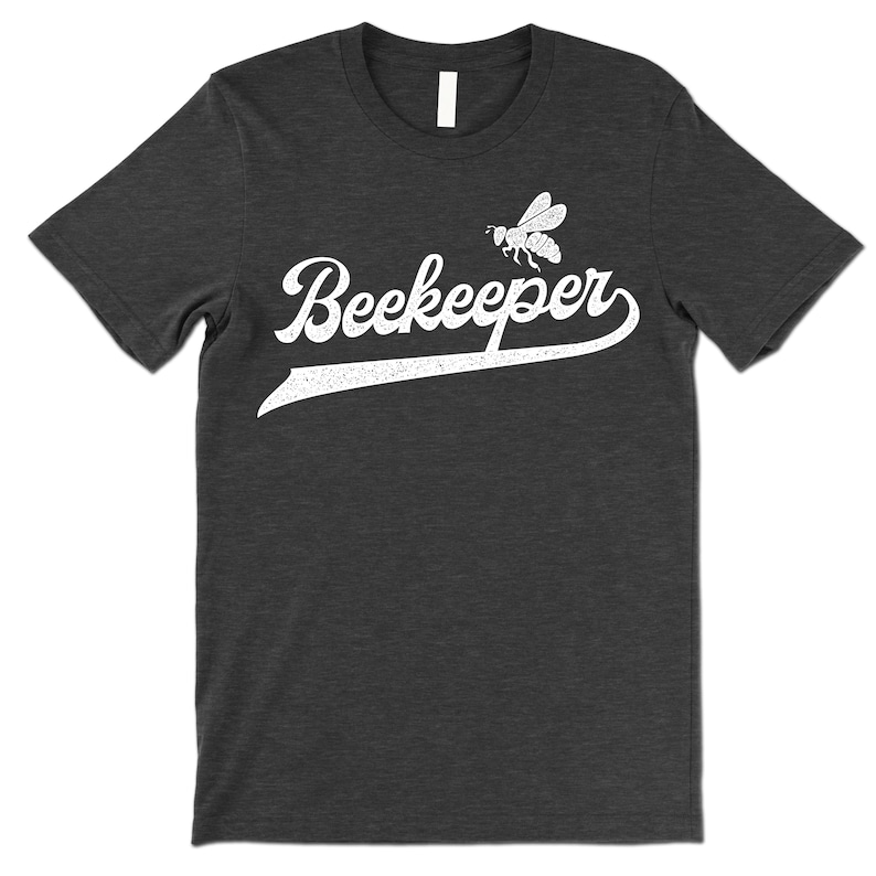 Puede incluir: Una camiseta gris oscuro jaspeada con un gr&aacute;fico blanco de estilo vintage de una abeja y la palabra "Beekeeper".