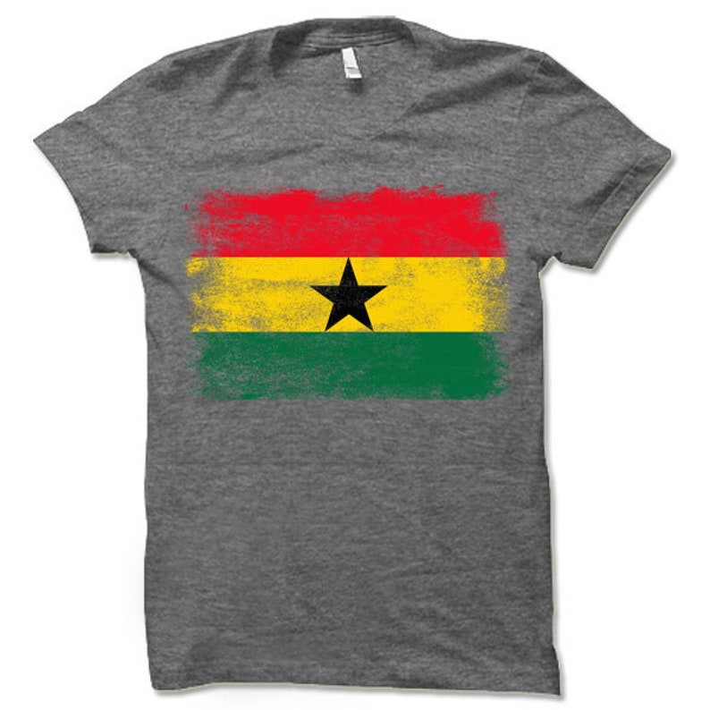 May include: A gray t-shirt with a distressed, faded design of the flag of Ghana. The flag features red, yellow, and green stripes with a black star in the center.