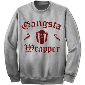 Pode incluir: Camisola cinzenta com a frase "Gangsta Wrapper" em fonte g&oacute;tica bord&ocirc;. O design inclui uma caixa de presente bord&ocirc; e gr&aacute;ficos de bengalas doces, criando um tema festivo.