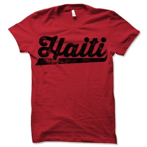 May include: Red t-shirt with a black vintage-style graphic that says "Haiti" in a bold font.