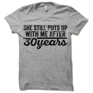 May include: Gray t-shirt with the text "She still puts up with me after 30 years" in black.