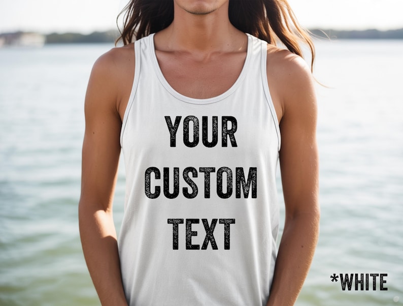 May include: White tank top with the text "YOUR CUSTOM TEXT" in black, with "*WHITE" at the bottom. The tank top has a racerback design and is made of a soft material. The background is a blurred view of water.