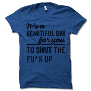 May include: Royal blue t-shirt with black text. The text reads "It's a BEAUTIFUL DAY for you TO SHUT THE FU*K UP". The shirt has a crew neck and short sleeves. A casual, humorous apparel item.