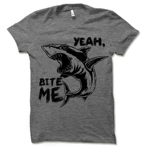 May include: A gray t-shirt with a black graphic of a shark with its mouth open and the text "Yeah, Bite Me".