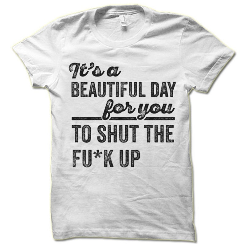 May include: White t-shirt with a crew neck and short sleeves. The shirt features black text that reads "It's a BEAUTIFUL DAY for you TO SHUT THE FU*K UP". The text is in a bold, distressed font.
