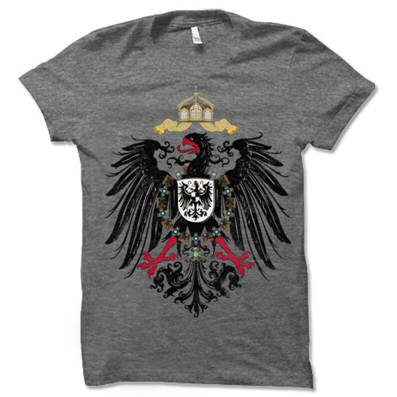 May include: A heather grey t-shirt with a black and white image of the German Imperial Eagle. The eagle is holding a shield with a black eagle on a white background. The eagle is surrounded by a wreath of gold and blue.