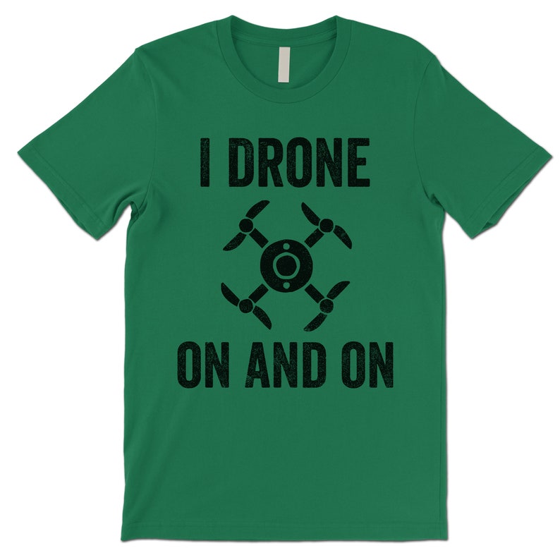 Op de afbeelding: Groen T-shirt met zwarte tekst die "I Drone On And On" luidt en een zwart silhouet van een drone.