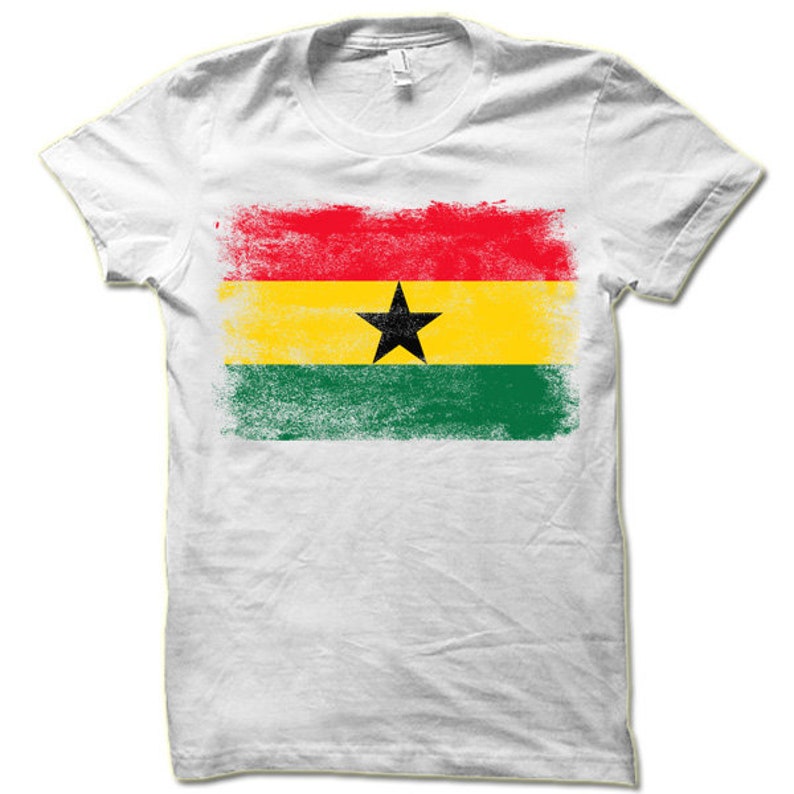 May include: White t-shirt with a distressed, faded print of the flag of Ghana. The flag is red, yellow, green, and black with a black star in the center.