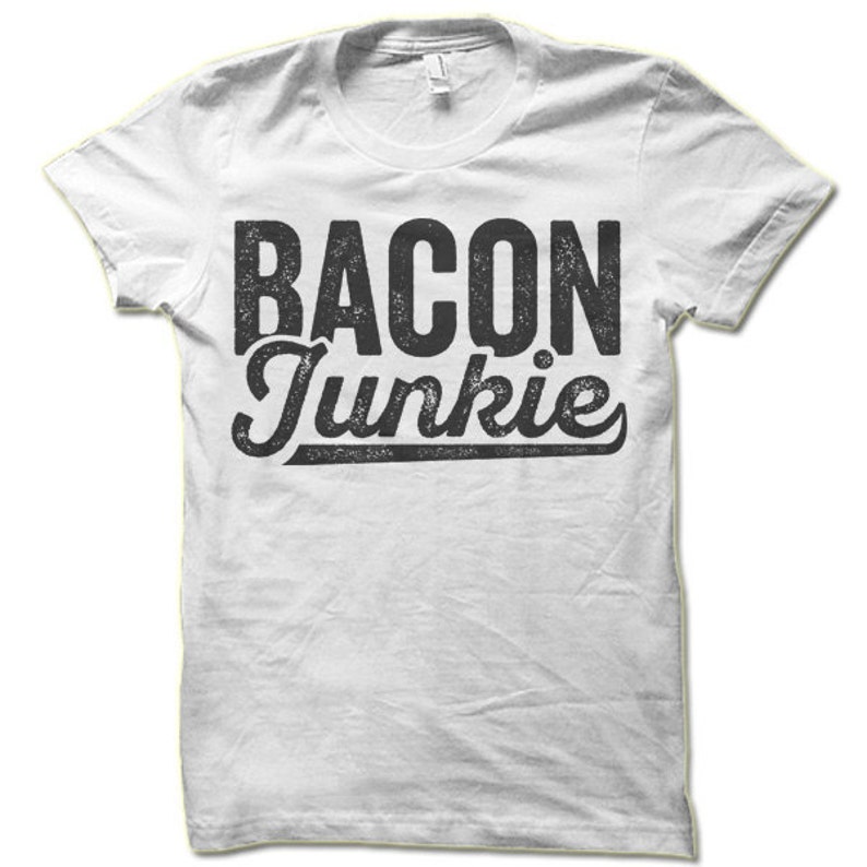May include: White t-shirt with black text that reads "BACON Junkie" in a distressed font.
