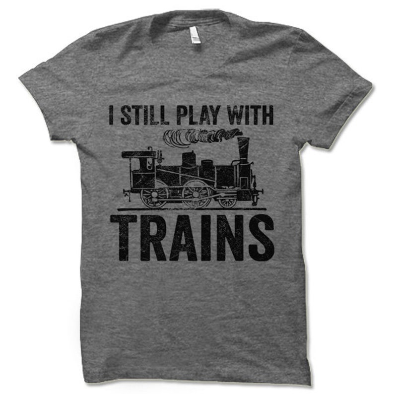 May include: A heather grey t-shirt with a vintage-style graphic of a train and the text "I still play with trains".