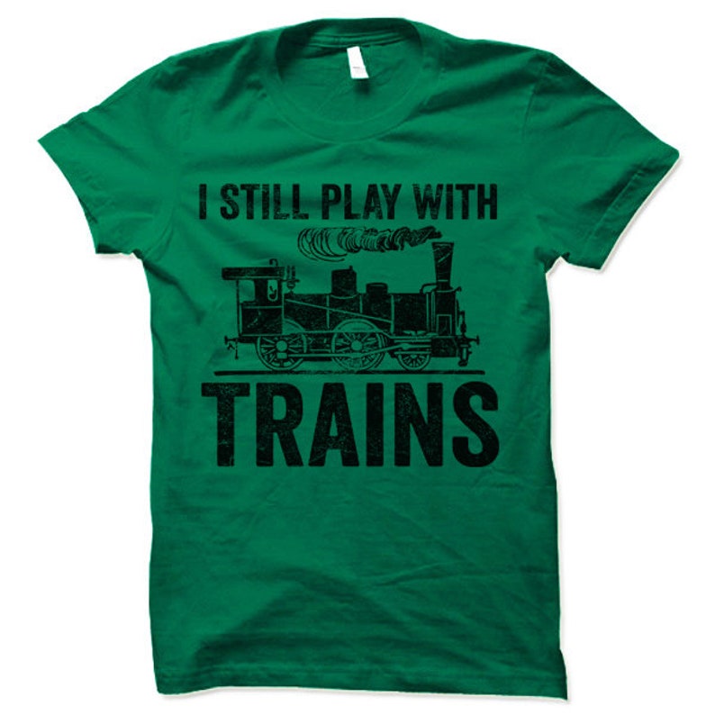 May include: A green t-shirt with a black graphic of a train and the text "I still play with trains".