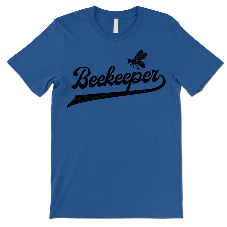 Puede incluir: Una camiseta azul real con un gr&aacute;fico de abeja negra y el texto "Beekeeper" en una fuente de b&eacute;isbol vintage.