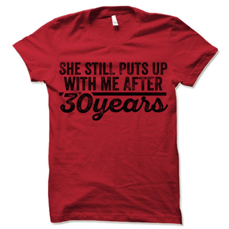 May include: Red t-shirt with black text that reads "She still puts up with me after 30 years".