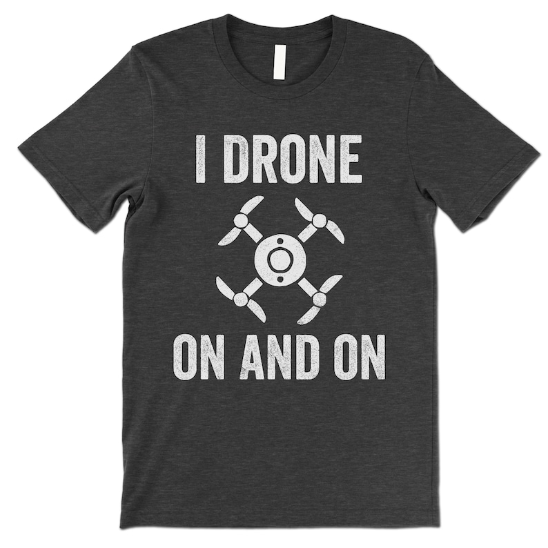 Op de afbeelding: Een donker grijs gem&ecirc;leerd t-shirt met een witte afbeelding van een drone en de tekst "I drone on and on".