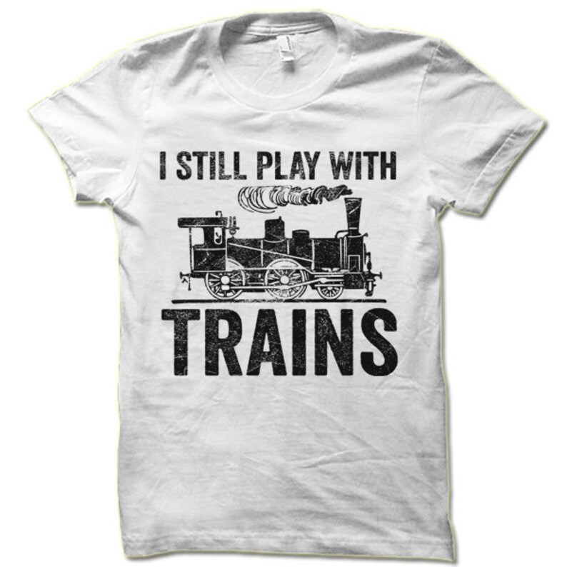 May include: White t-shirt with a black graphic of a train and the text "I still play with trains".