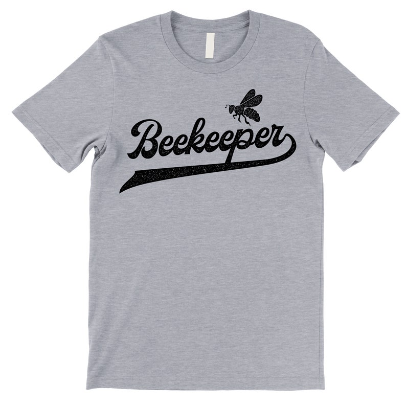 Puede incluir: Una camiseta gris jaspeada con un gr&aacute;fico negro de una abeja y el texto "Beekeeper" en una fuente de b&eacute;isbol vintage.