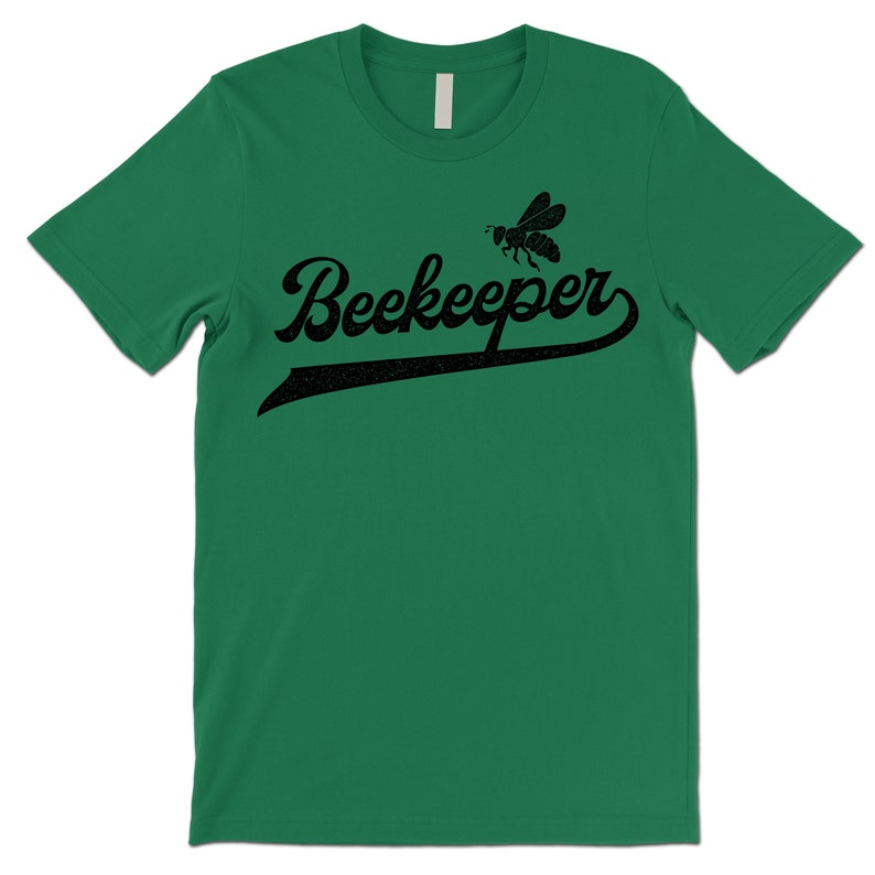 Puede incluir: Una camiseta verde con una abeja negra y el texto "Beekeeper" en una fuente de b&eacute;isbol vintage.