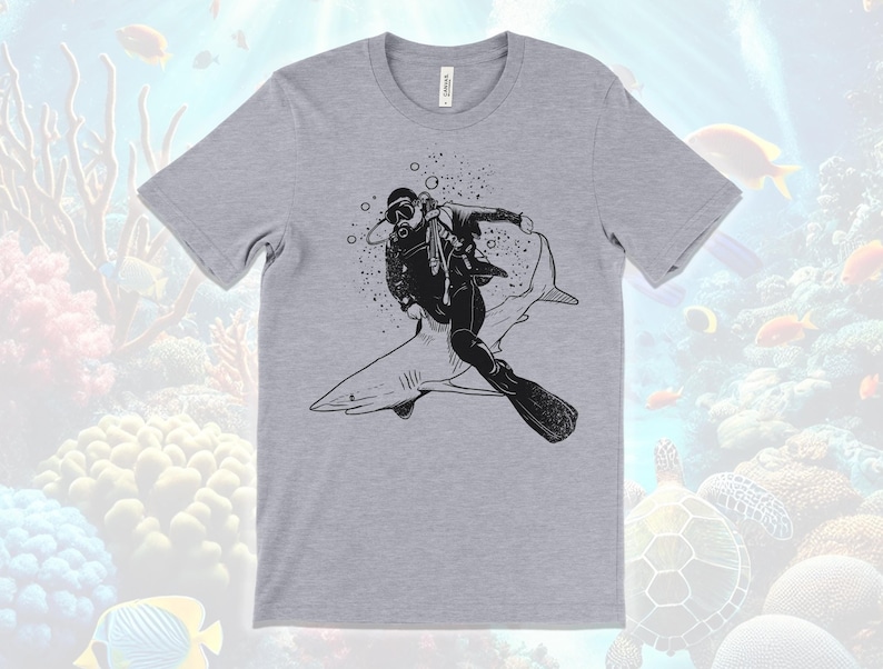Scuba diver riding a shark graphic on a white adventure-themed kids shirt