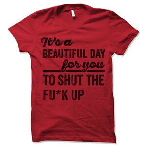 May include: Red t-shirt with black text that reads "It's a BEAUTIFUL DAY for you TO SHUT THE FU*K UP". The shirt is a crew neck style and appears to be made of cotton.