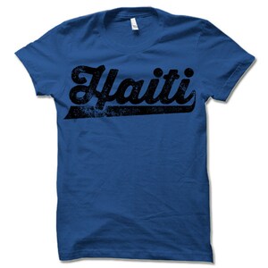 May include: A royal blue t-shirt with a black distressed graphic of the word "Haiti" in a retro font.