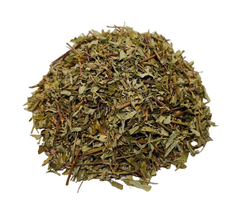 May include: A pile of dried green herbs with brown stems and leaves. The herbs are densely packed together, creating a textured appearance. The image is set against a plain white background.