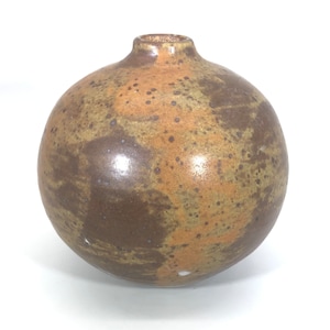 Może przedstawiać: Runda, brązowa ceramiczna wazon z pstrokatą glazurą. Wazon ma szeroką podstawę i wąską szyjkę.